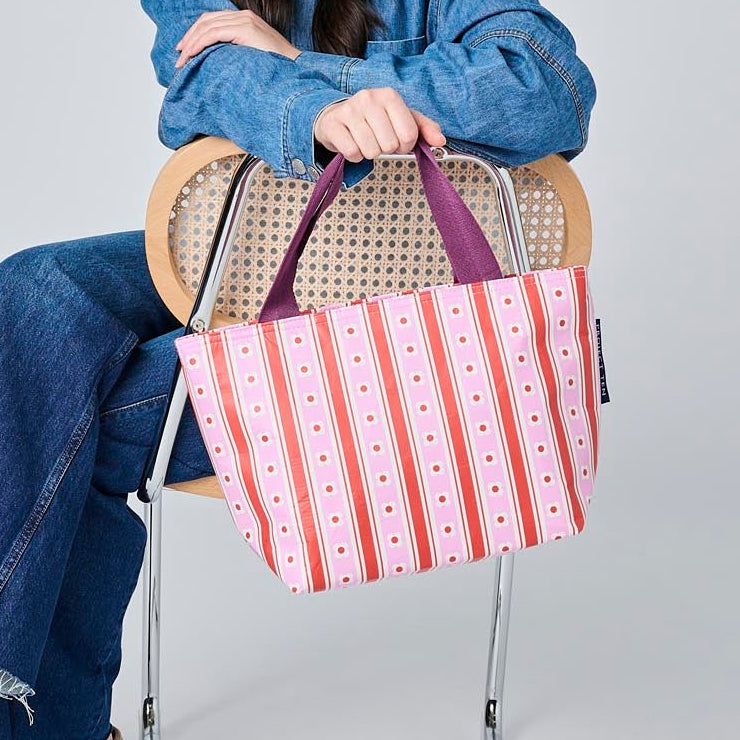 Someone holding the Mini Tote in Wallpaper, using the soft woven handles.
- Project Ten