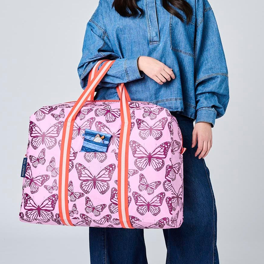 Someone holding the Overnight Bag using the soft woven handles. There is a glasses case in the front pocket of the Overnight Bag.
- Project Ten