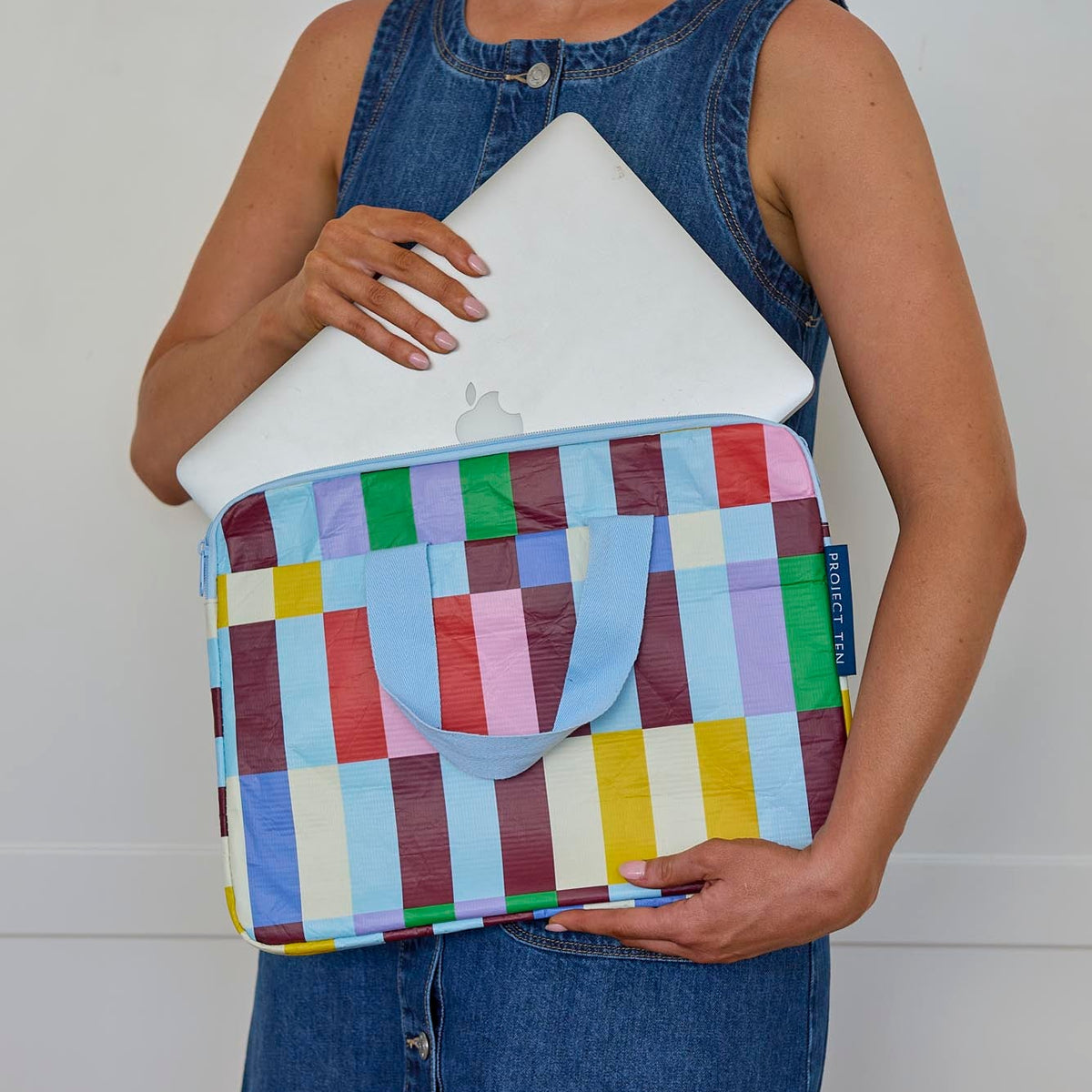 Someone placing a laptop into the Laptop Case – Multi Stripe - Project Ten