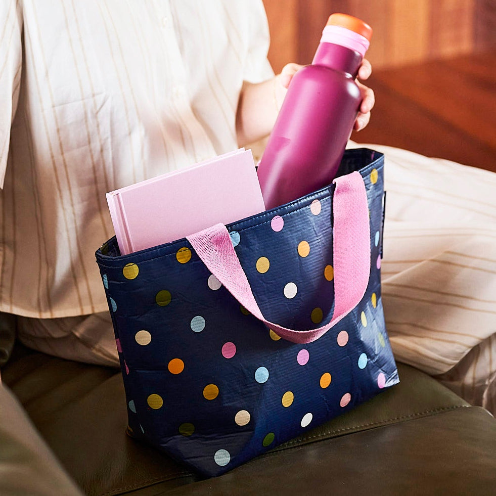 Person holding a pink drink bottle in a Mini Tote – Confetti
Polka dots on navy background- Project Ten