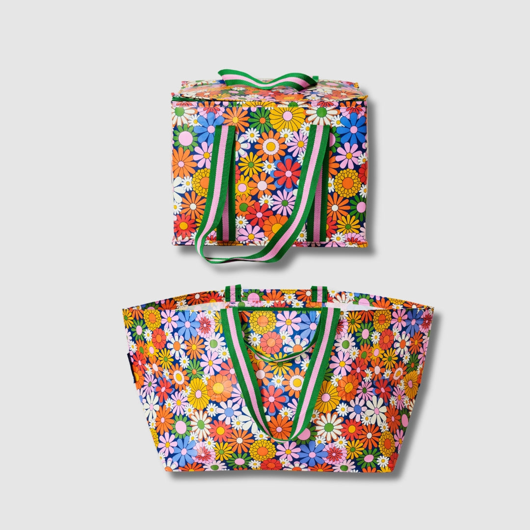 Our Coastal Floral Beach Large Shopping Bundle, a zip-top Large Insulated Tote and Oversized Tote in a retro daisy print of orange, red, pink, yellow, blue and white flowers on a navy background, each with green and pink striped carry handles.
