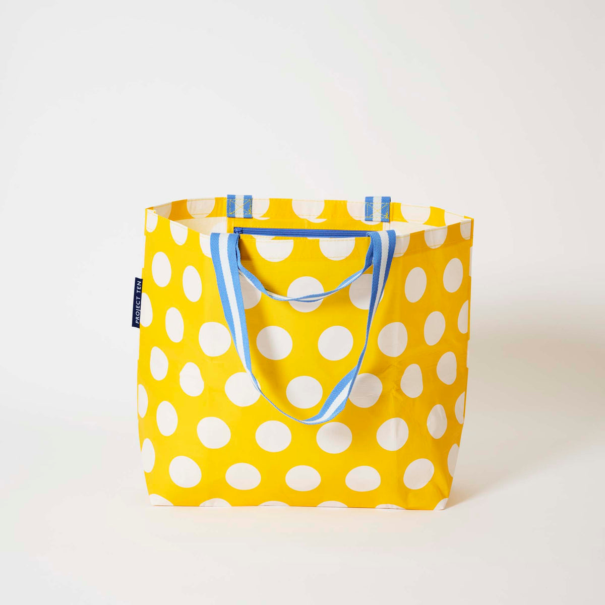Our Yellow Polka Dot Medium Tote in bright yellow with ecru polka dots and blue and ecru striped straps, shown open against a plain background.