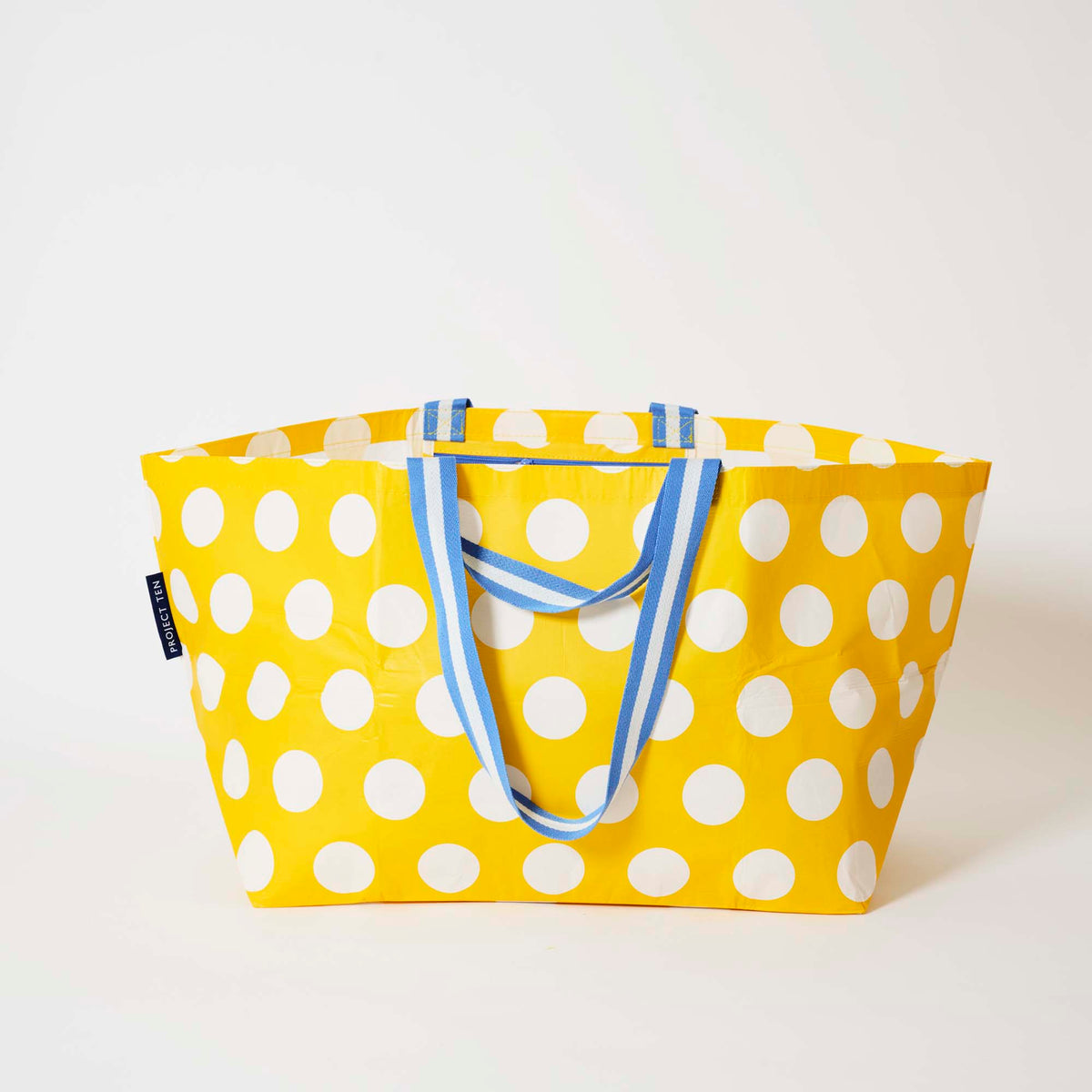Our Yellow Polka Dot Oversized Tote in bright yellow with ecru polka dots and blue and white striped straps, shown open against a plain background.