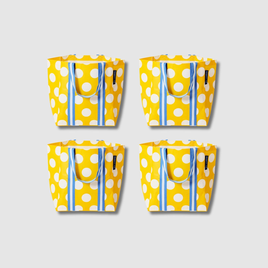 Our Yellow Polka Dot Shopper Tote Bundle, a set of four Shopper Totes in bright yellow with large ecru polka dots, each with blue and ecru striped carry handles.