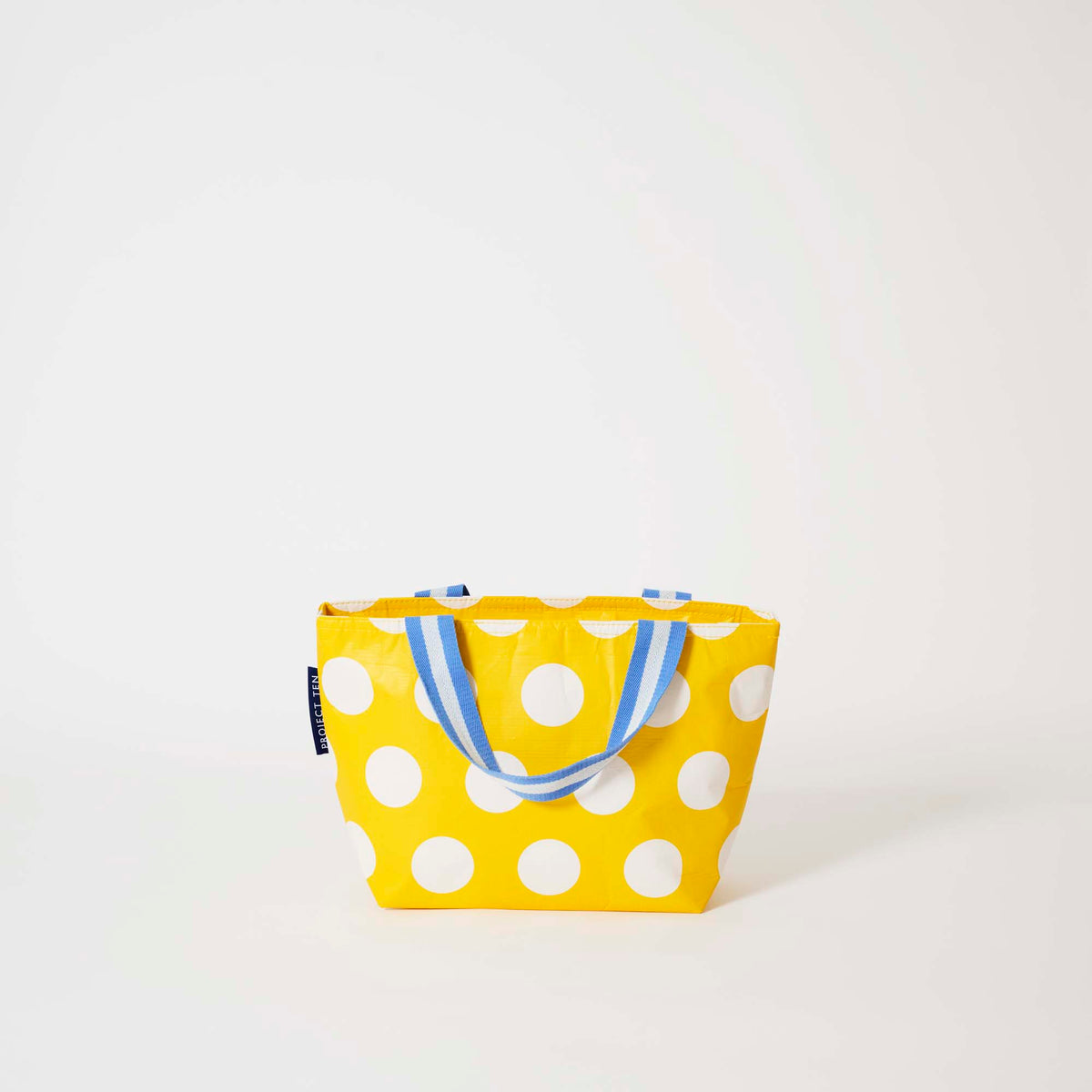 Our Yellow Polka Dot Mini Tote, a compact tote bag in bright yellow with large ecru polka dots and two blue and ecru striped carry handles.