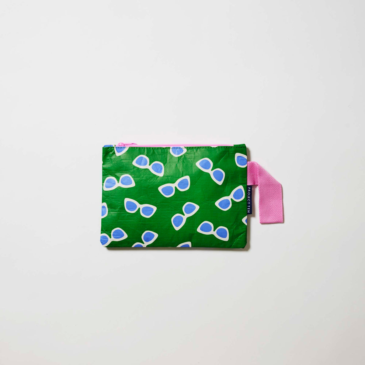 Our Sunglasses Mini Zip Pouch, a small rectangular pouch in green with a scattered print of ecru framed sunglasses with blue lenses, and a pink zip and handle.