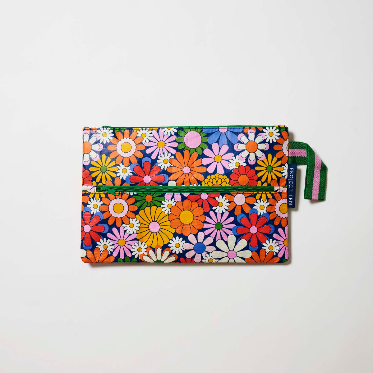 Our Coastal Floral Pencil Case, a flat rectangular case covered in bright retro daisies in orange, pink, yellow and blue on a navy background, with two green zip compartments and a green and pink striped handle.