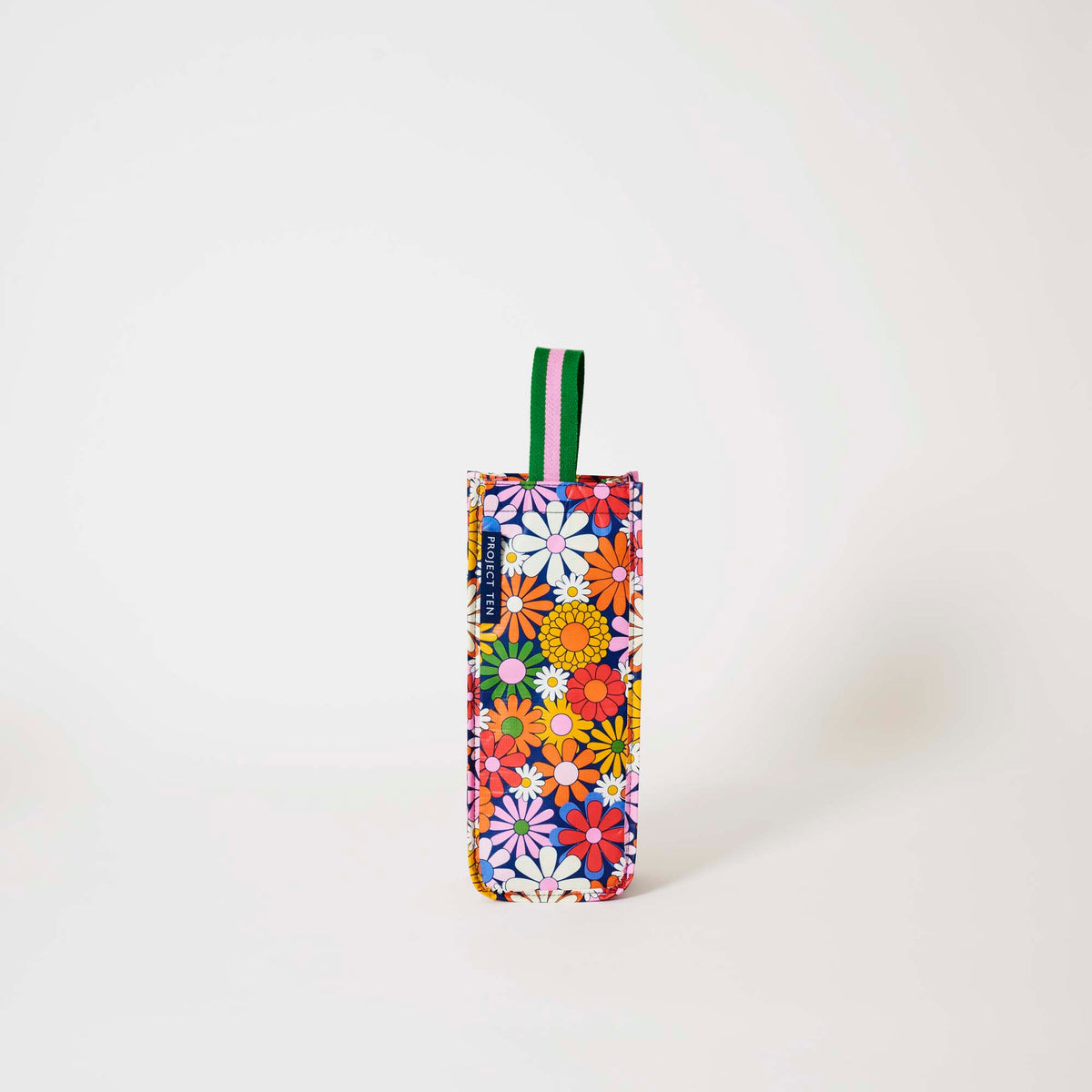 Our Coastal Floral Wine Bag, a tall narrow bottle bag in a retro daisy print of orange, red, pink, yellow and white flowers on a navy background, with a single green and pink striped carry handle.