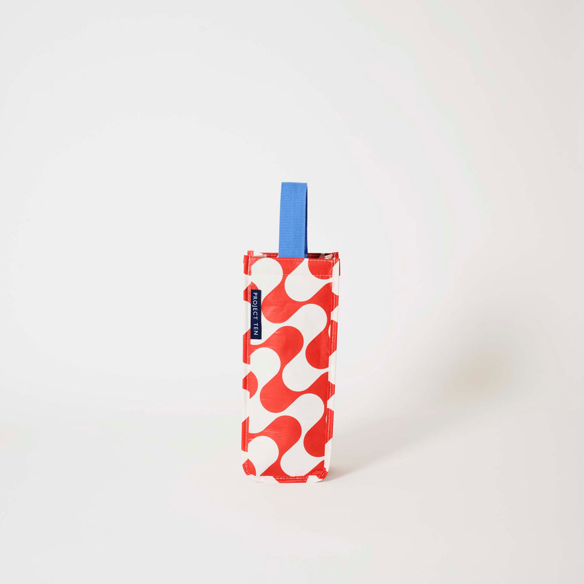 Our Red Ripple Wine Bag, a tall narrow bottle bag in a red and ecru wave print with a single blue carry handle.