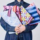 A person holding the Large Zip Pouches. Wallpaper, Butterfly, Toile, Mosaic and Blue Stripe. 
- Project Ten
