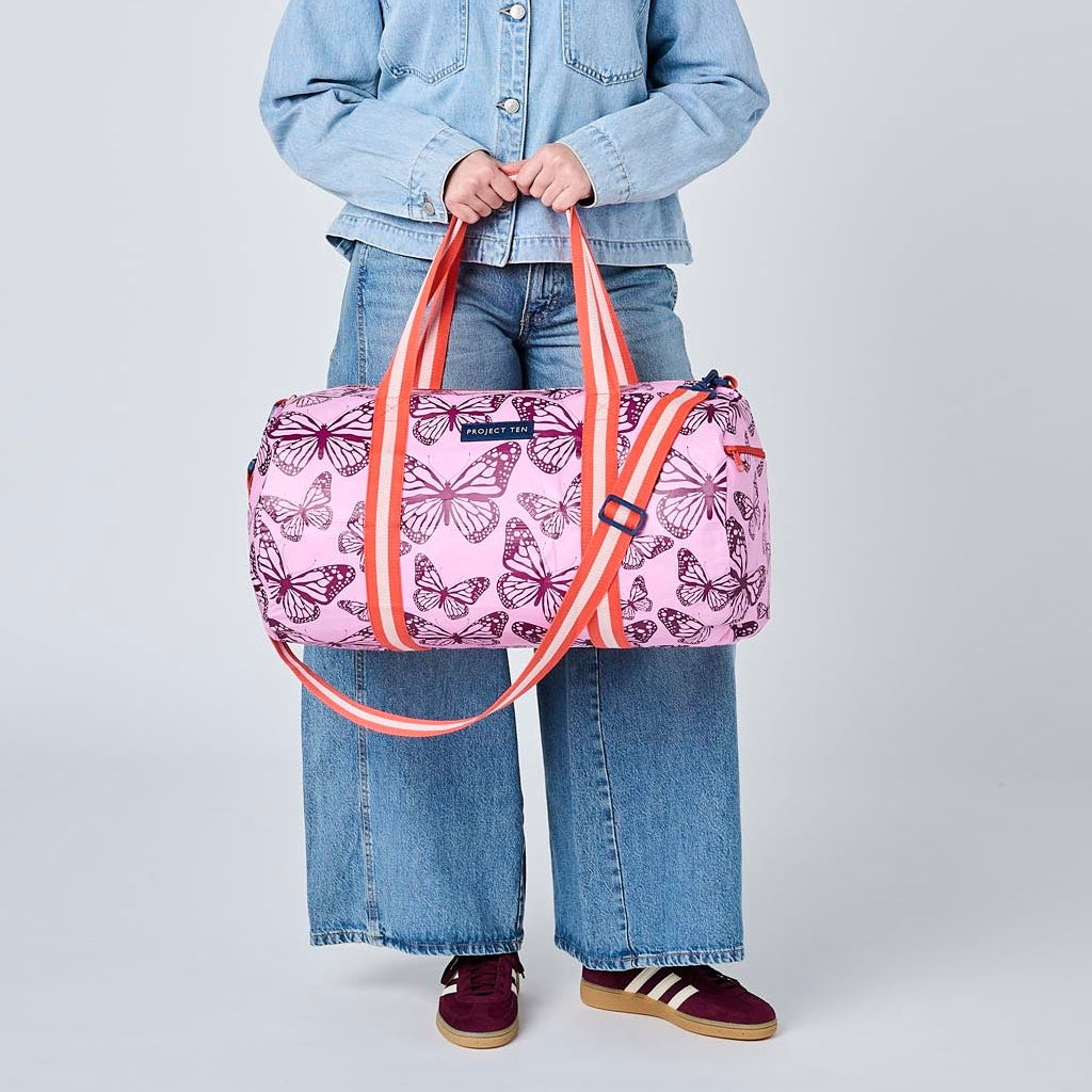 Someone holding the Barrel Bag in Butterfly using the soft woven handles. 
- Project Ten