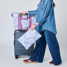 Someone pushing a suitcase with the Zip Medium Tote on top using the luggage band. 
They are holding a Large Zip Pouch in their hand. 
- Project Ten