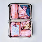 Wallpaper packing cubes packed inside a suitcase showing clothing, shoes, sunglasses case and mini zip pouch packed away. 