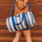 Someone holding the Barrel Bag in Oxford Stripe using the shoulder strap 
- Project Ten