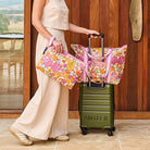 Someone pushing a suitcase with a Medium Zip Tote using the travel band.
In the other hand they are holding the Large Zip Pouch

- Project Ten