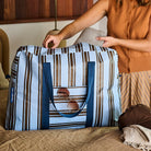 Someone placing an item in the Oxford Stripe Overnight Bag 

 - Project Ten
