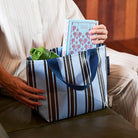 Someone placing a book and water bottle in the Oxford Stripe Mini Tote

- Project Ten