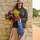 Wine Bag – Confetti - Project Ten
Person holding flowers and polka dot wine bag. 
Polka dots on navy background.