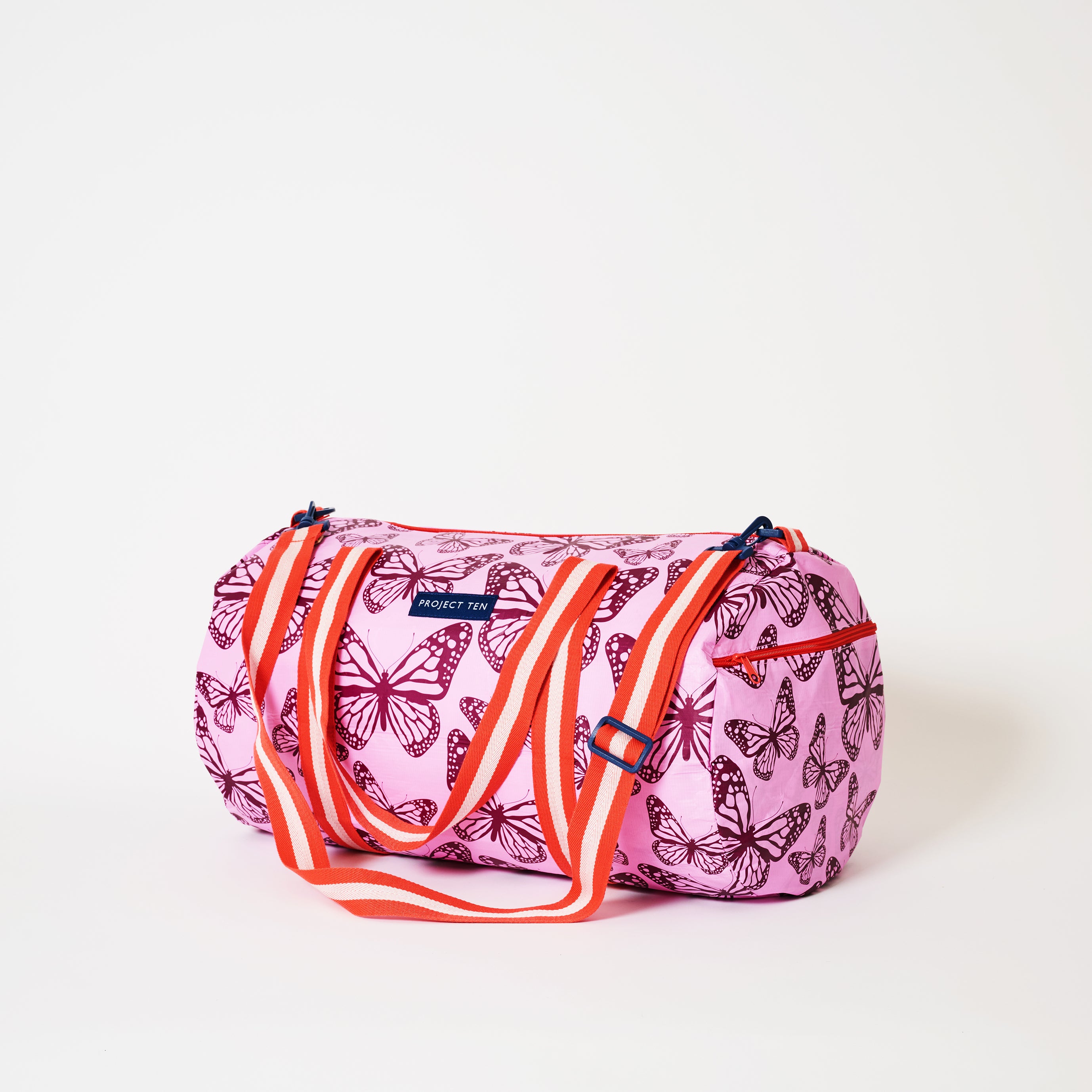 Barrel Bag with soft woven shoulder strap and handles in Butterfly  The image also shows a zip compartment on the end of the Barrel Bag.  
- Project Ten