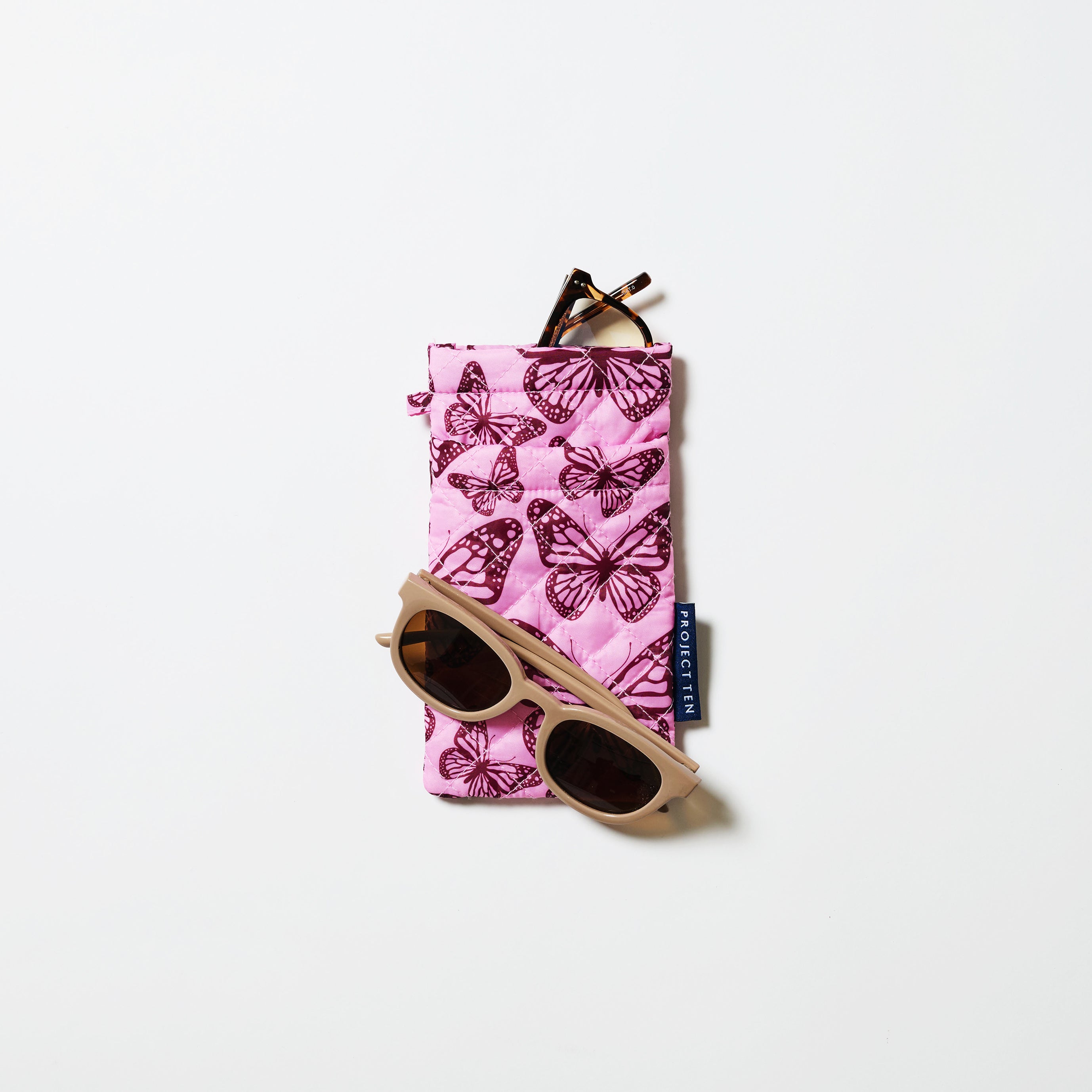 Double Glasses case in Butterfly. Image shows reading glasses sitting the top pocket and sunglasses resting on the case. 
- Project Ten