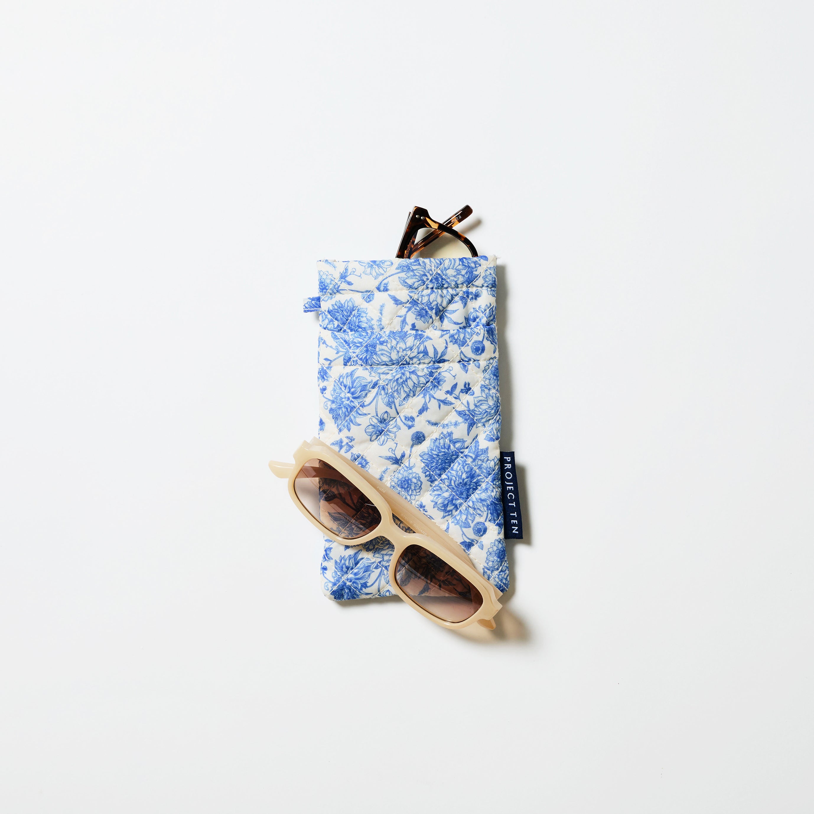 Double Glasses Case in Toile. A set of reading glasses sit in the top pocket and sunglasses are resting on the case. 
- Project Ten