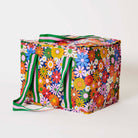 Our Coastal Floral Large Insulated Tote, a large boxy cooler bag covered in bright retro daisies in orange, pink, yellow and blue on a navy background, with a fold-over zip lid, long green and pink striped shoulder straps and a short green and pink striped top handle.