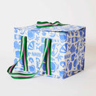 Our Feast Large Insulated Tote, a large boxy cooler bag in a blue and ecru print of shells, beach umbrellas, sunglasses, gelato and the word "Ciao", with a fold-over zip lid, long green and pink striped shoulder straps and a short green and pink striped top handle.