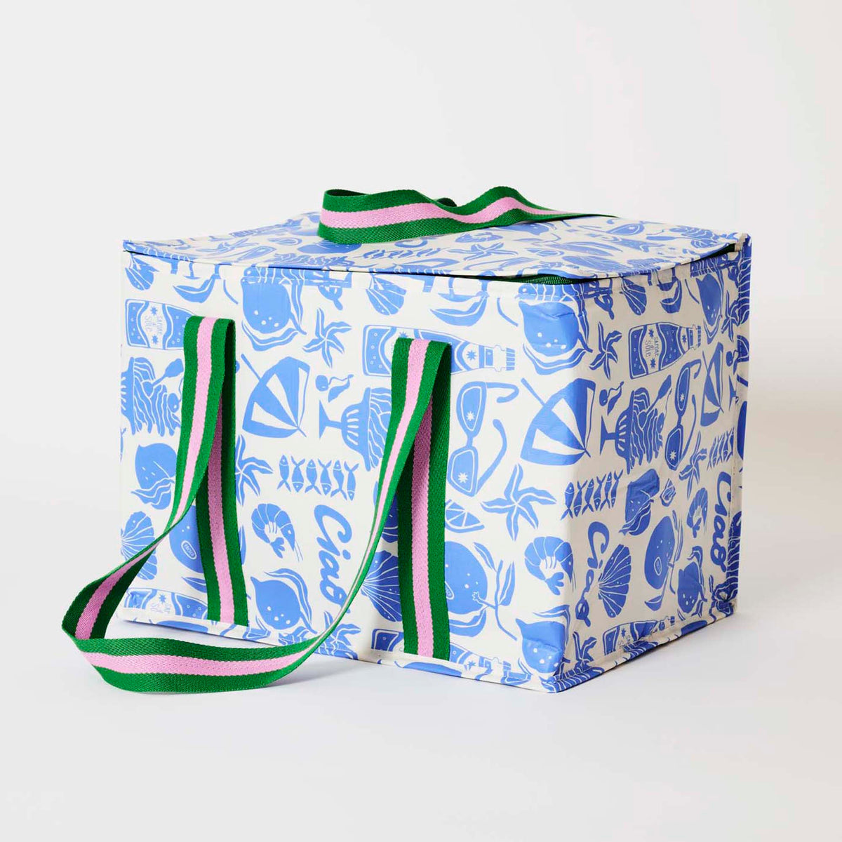 Our Feast Large Insulated Tote, a large boxy cooler bag in a blue and ecru print of shells, beach umbrellas, sunglasses, gelato and the word "Ciao", with a fold-over zip lid, long green and pink striped shoulder straps and a short green and pink striped top handle.