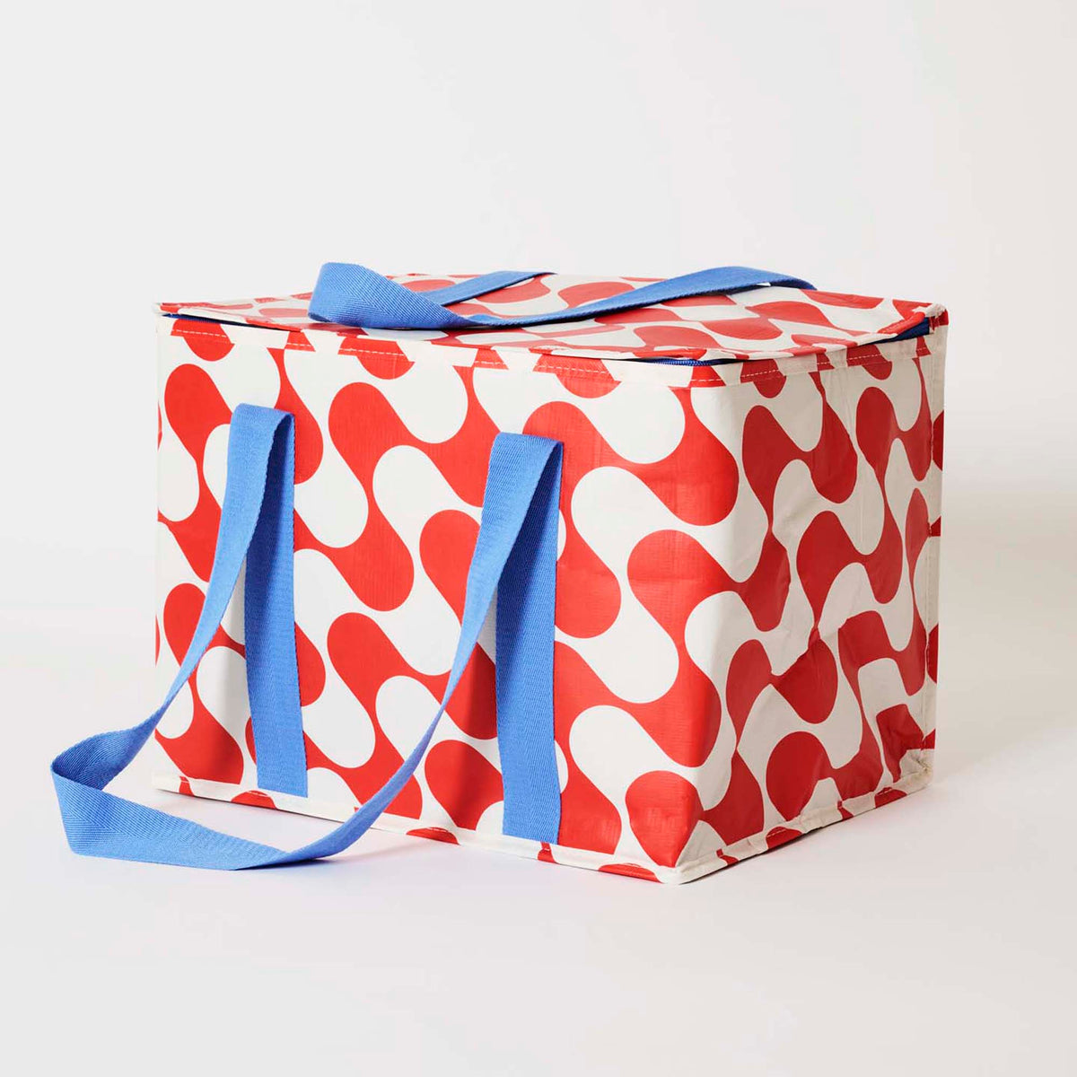 Our Red Ripple Large Insulated Tote, a large boxy cooler bag in a red and ecru wave print with a fold-over zip lid, long blue shoulder straps and a short blue top handle.