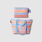 Our Capri Stripe Large Zip Pouch and Zip Medium Tote Bundle, a Zip Medium Tote with a vertical striped front pocket and a matching Large Zip Pouch in pink, orange, blue and ecru stripes, with blue and ecru striped carry handles and a loop tab.