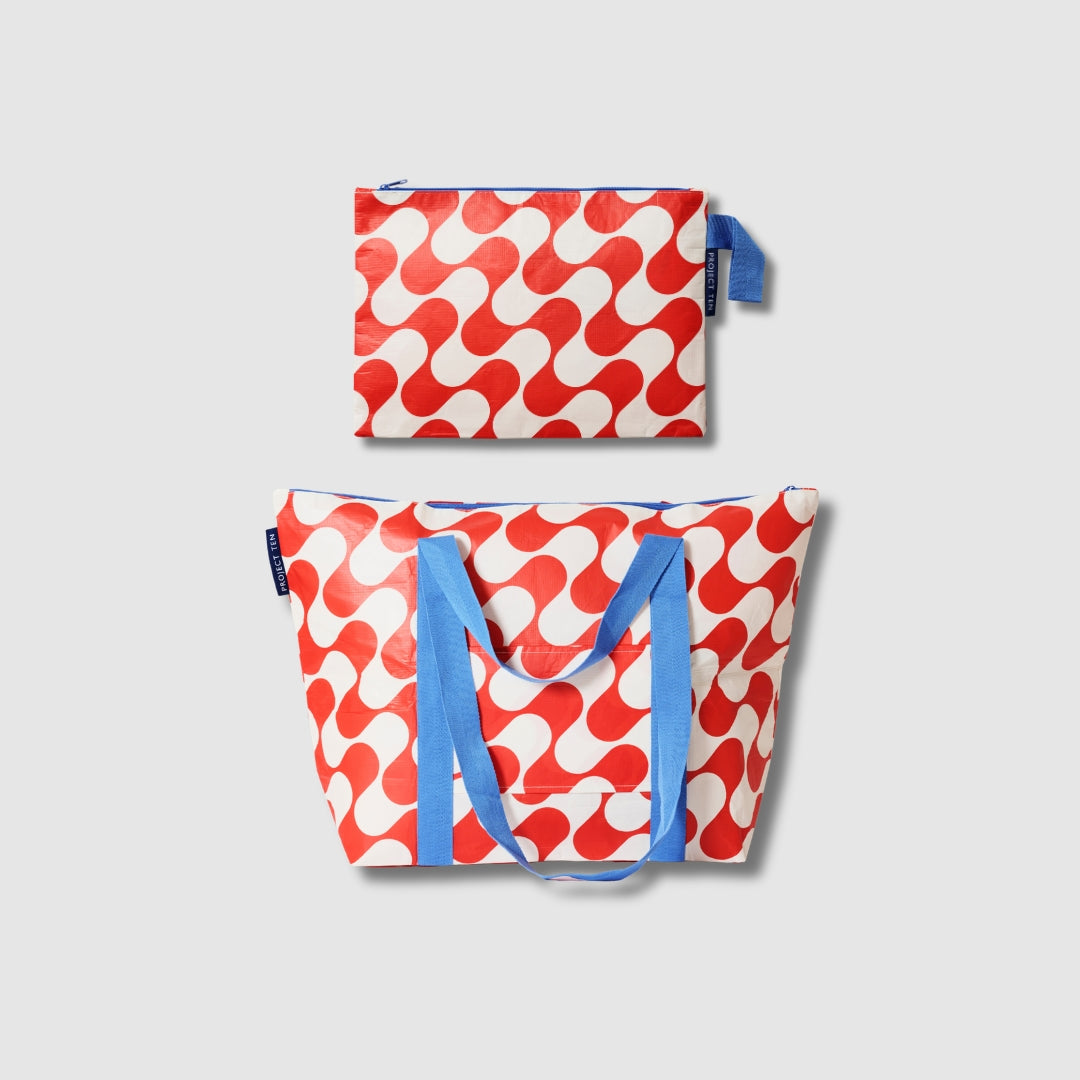 Our Red Ripple Large Zip Pouch and Zip Medium Tote Bundle, a Zip Medium Tote and a matching Large Zip Pouch in a bold geometric wave print of red and ecru, with blue carry handles and a loop tab.