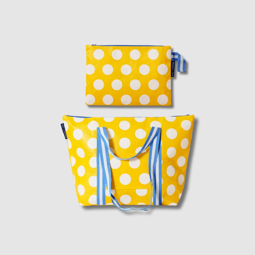 Our Yellow Polka Dot Large Zip Pouch and Zip Medium Tote Bundle, a Zip Medium Tote and a matching Large Zip Pouch in bright yellow with large ecru polka dots, with blue and ecru striped carry handles and a loop tab.