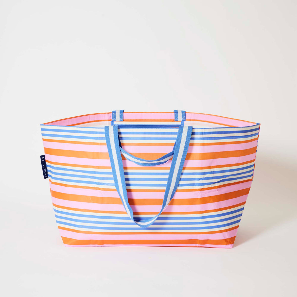 Our Capri Stripe Oversized Tote in horizontal stripes of pink, orange, blue and ecru with blue and white striped straps, shown open against a plain background.
