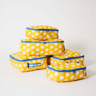 Our Yellow Polka Dot Packing Cubes, a set of five zip-up packing cubes in different sizes, in bright yellow with large ecru polka dots, with blue zips and blue and ecru striped carry handles.