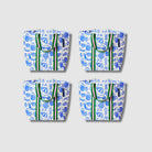 Our Feast Shopper Tote Bundle, a set of four Shopper Totes in an ecru base with a blue seaside print of shells, oranges, sunglasses, beach umbrellas and "Ciao" lettering, each with green and pink striped carry handles.