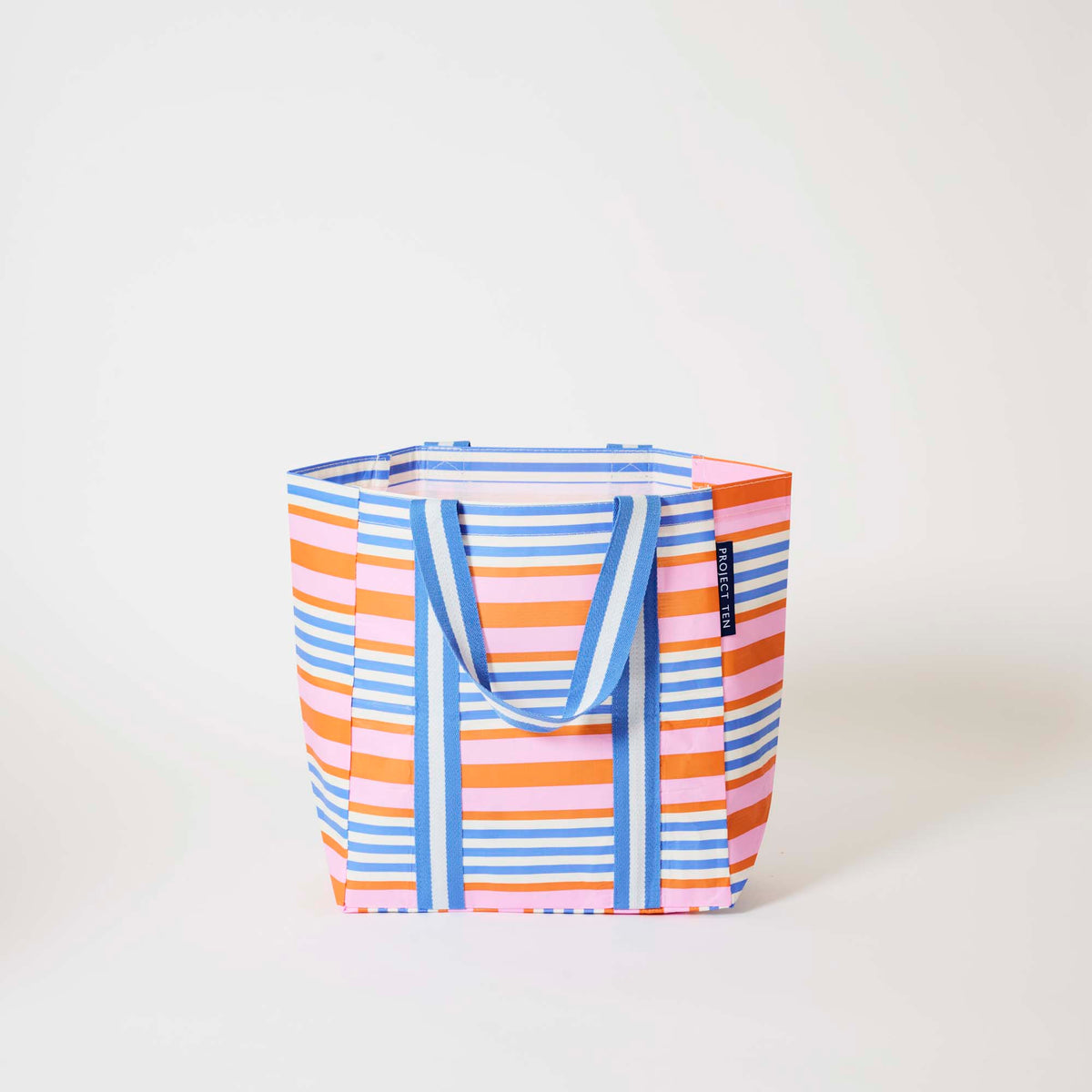 Our Capri Stripe Shopper Tote in horizontal stripes of pink, orange, blue and ecru, with blue and ecru striped straps that run down the front and back, shown open against a plain background.