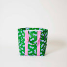 Our Sunglasses Shopper Tote in green with a scattered print of ecru framed sunglasses with blue lenses, and pink straps that run down the front and back, shown open against a plain background.