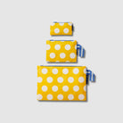 Our Yellow Polka Dot Zip Pouch Bundle, a set of three Zip Pouches in small, medium and large in bright yellow with large ecru polka dots, with blue and ecru striped loop tabs on the medium and large pouches.