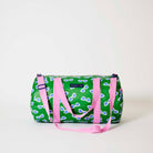 Our Sunglasses Barrel Bag, a cylindrical duffle-style bag in green with a scattered print of blue-lensed, white-framed sunglasses, two pink carry handles, a detachable pink shoulder strap and a pink zip.