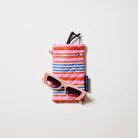 Our Capri Stripe Double Glasses Case, a soft quilted glasses case in pink, orange, blue and ecru horizontal stripes, with a squeeze-top opening and a small loop tab.