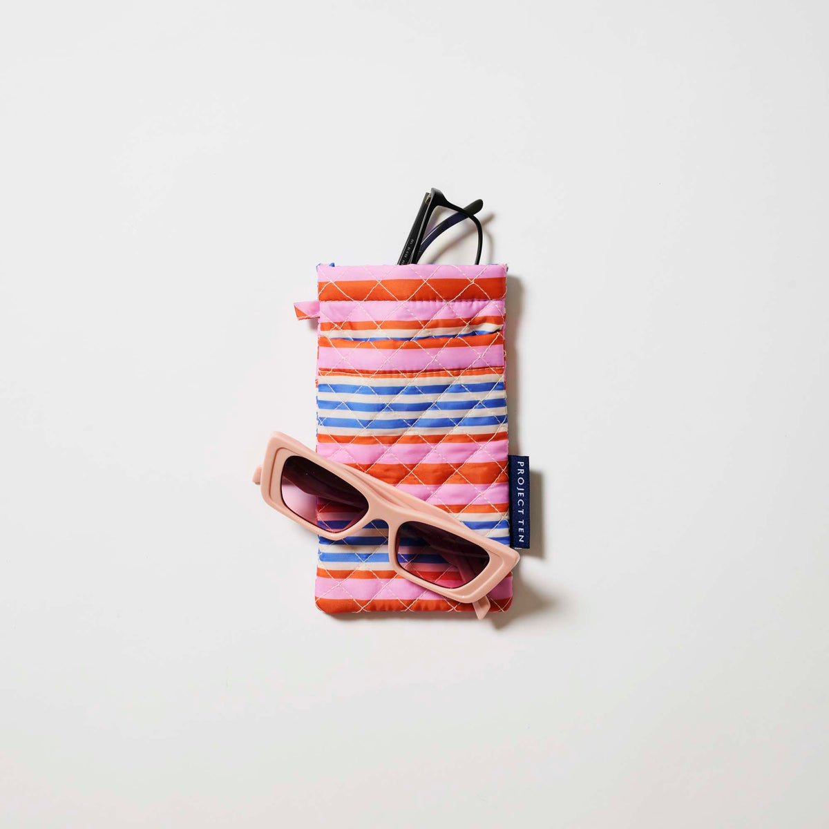 Our Capri Stripe Double Glasses Case, a soft quilted glasses case in pink, orange, blue and ecru horizontal stripes, with a squeeze-top opening and a small loop tab.