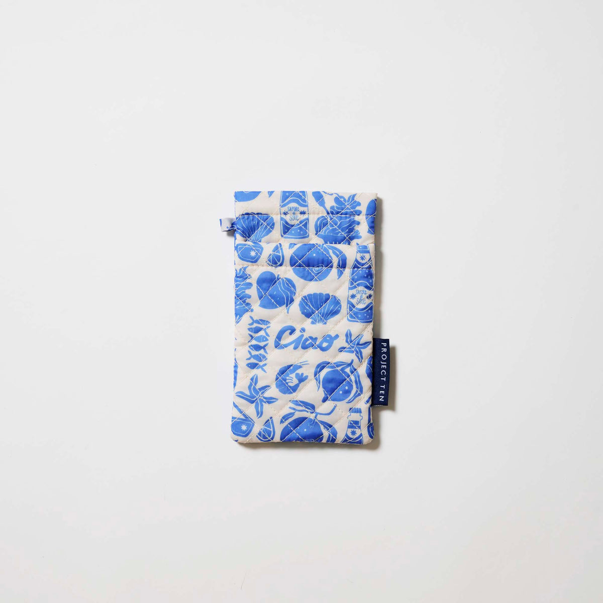 Our Feast Double Glasses Case, a soft quilted glasses case in an ecru base with a blue seaside print of shells, sardines, oranges, soda bottles and "Ciao" lettering, with a squeeze-top opening and a small loop tab.