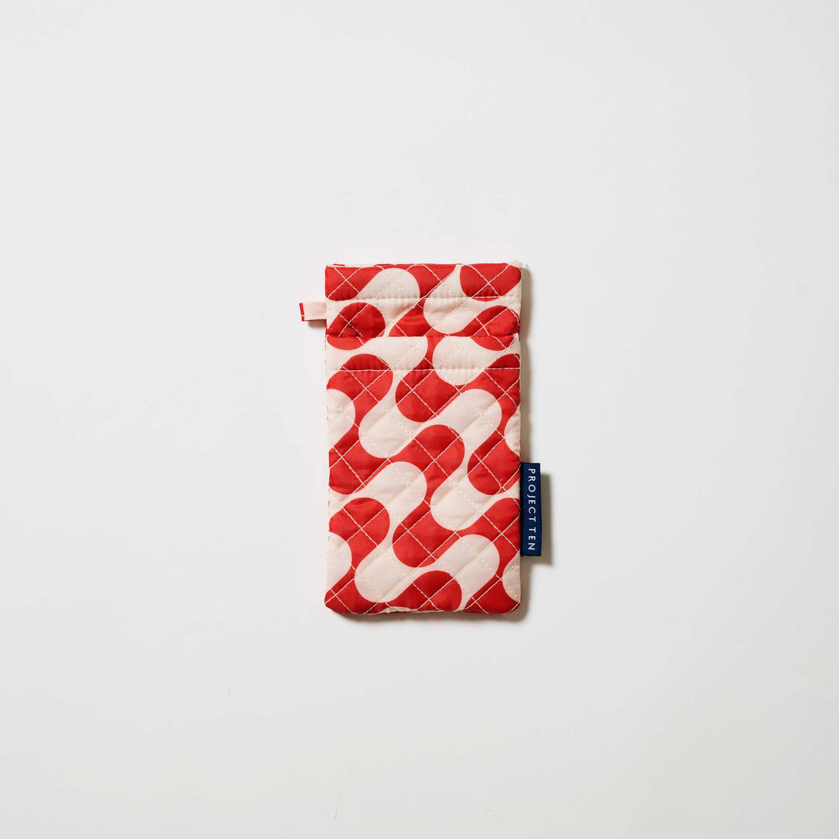Our Red Ripple Double Glasses Case, a soft quilted glasses case in a bold geometric wave print of red and ecru, with a squeeze-top opening and a small loop tab.
