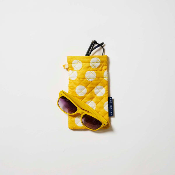 Our Yellow Polka Dot Double Glasses Case, a soft quilted glasses case in bright yellow with large ecru polka dots, with a squeeze-top opening and a small loop tab.