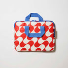 Our Red Ripple Laptop Case, a slim zip-up laptop case in a bold geometric wave print of red and ecru, with two blue carry handles and a blue zip.