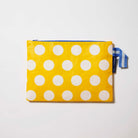 Our Yellow Polka Dot Large Zip Pouch, a flat rectangular pouch in bright yellow with ecru polka dots and a blue zip and blue and ecru striped handle.