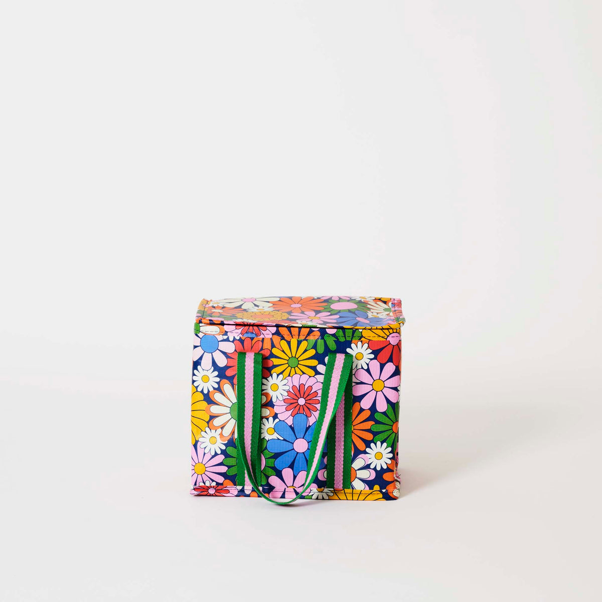 Our Coastal Floral Mini Insulated Tote, a small boxy cooler bag covered in bright retro daisies in orange, pink, yellow and blue on a navy background, with a fold-over zip lid and short green and pink striped carry handles.