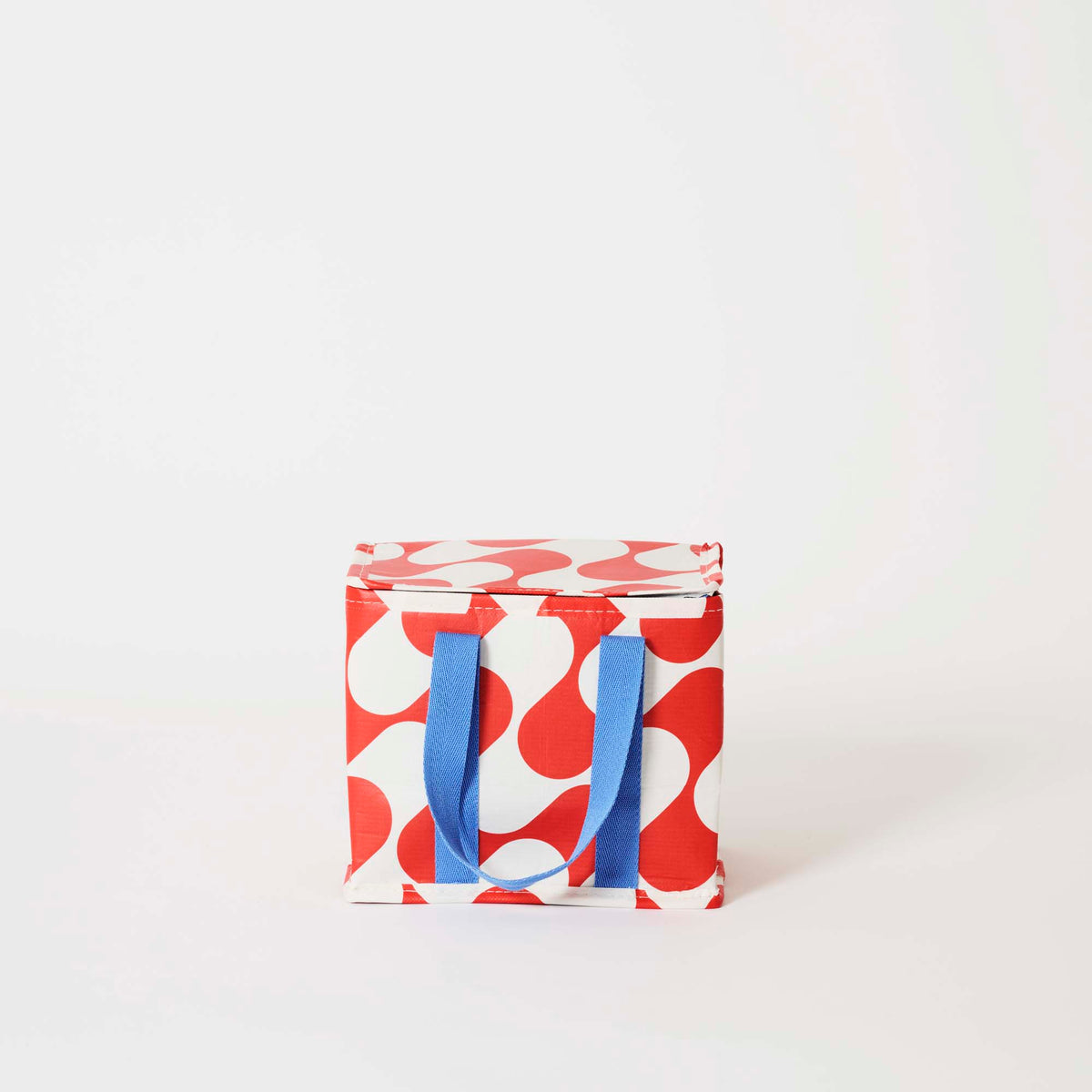 Our Red Ripple Mini Insulated Tote, a small boxy cooler bag in a red and ecru wave print with a fold-over zip lid and short blue carry handles.