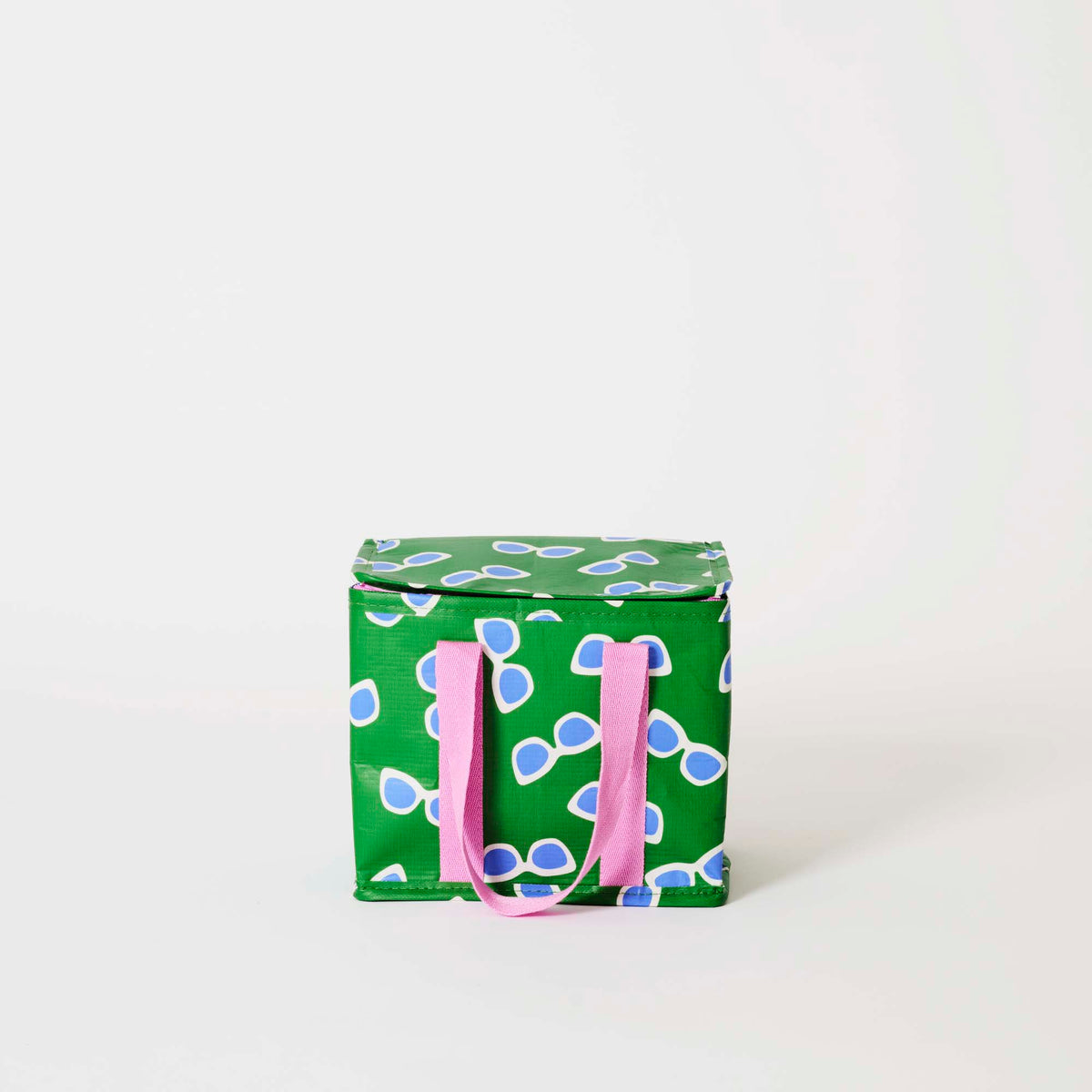 Our Sunglasses Mini Insulated Tote, a small boxy cooler bag in green with a scattered print of ecru framed sunglasses with blue lenses, a fold-over zip lid and short pink carry handles.