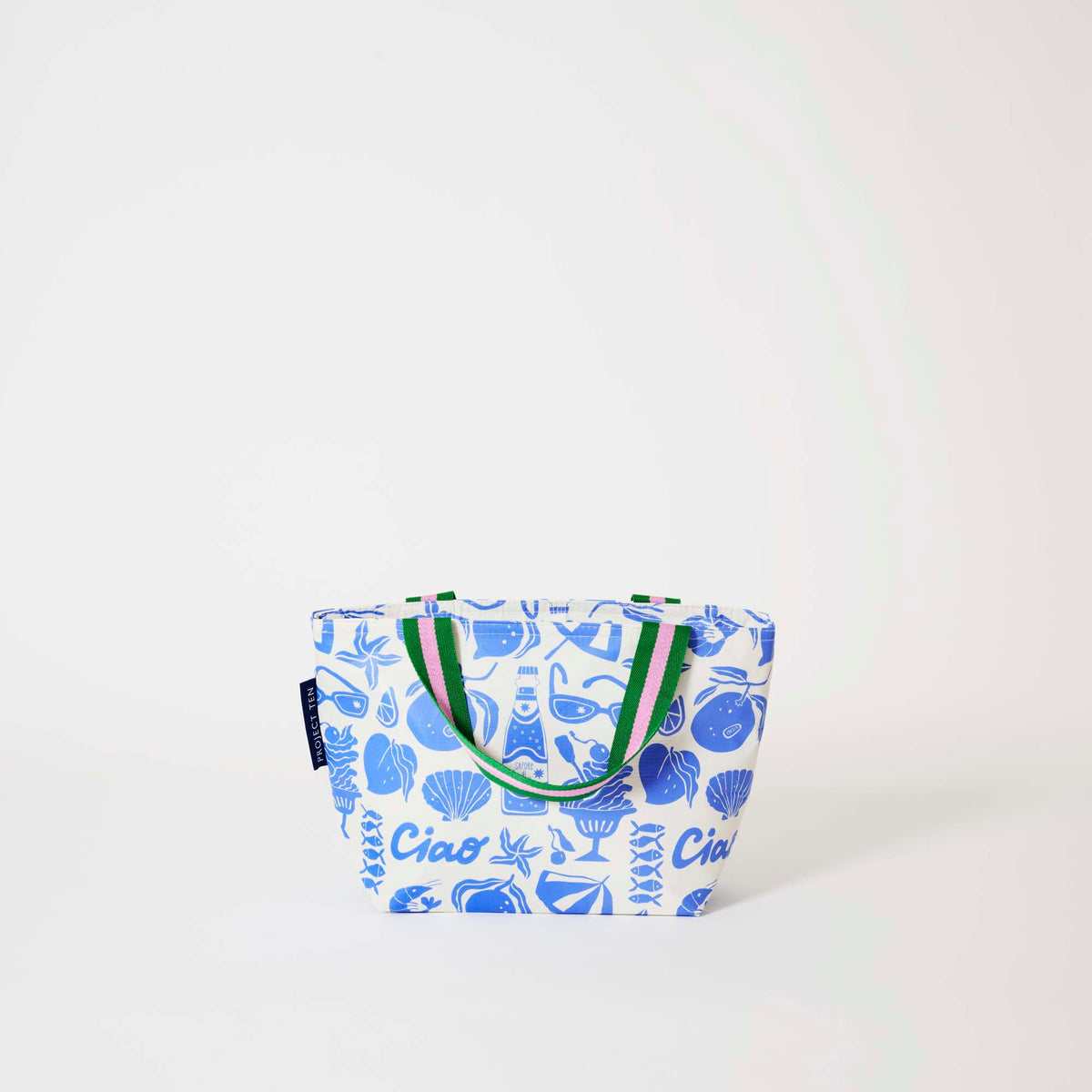 Our Feast Mini Tote, a compact tote bag in an ecru base with a blue seaside print of sunglasses, ice cream sundaes, oranges, shells, sardines and "Ciao" lettering, with two green and pink striped carry handles.